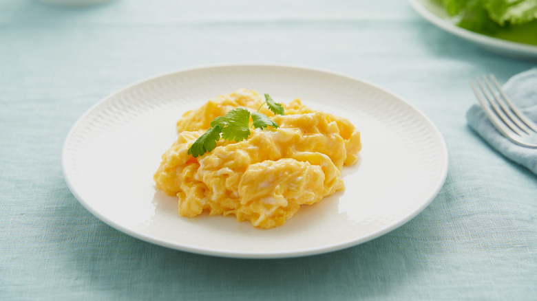 Plate of scrambled eggs with sprig of parsley