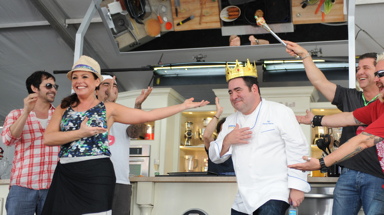 Rachael Ray standing on stage with Emeril Lagasse, who's wearing a crown