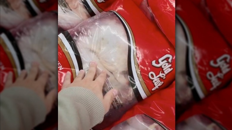 hand touching chicken with air in bag