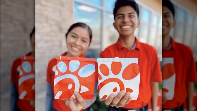 Two people holding Chick-fil-A bags