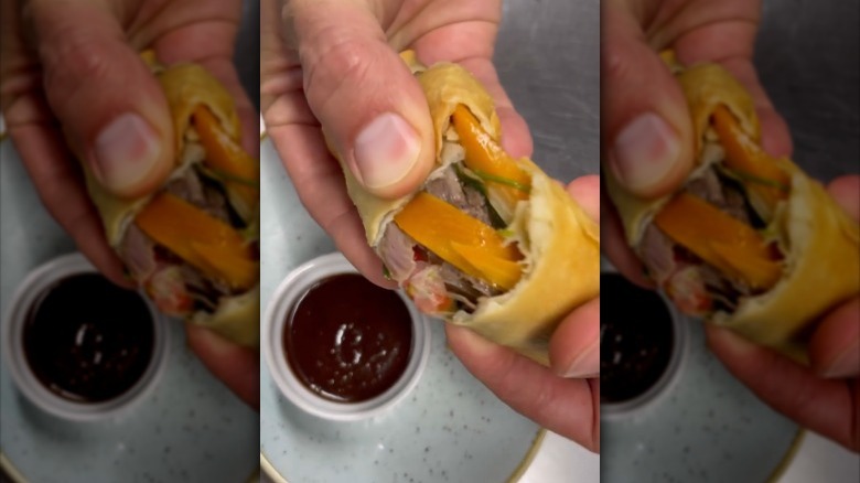 fingers holding duck spring rolls