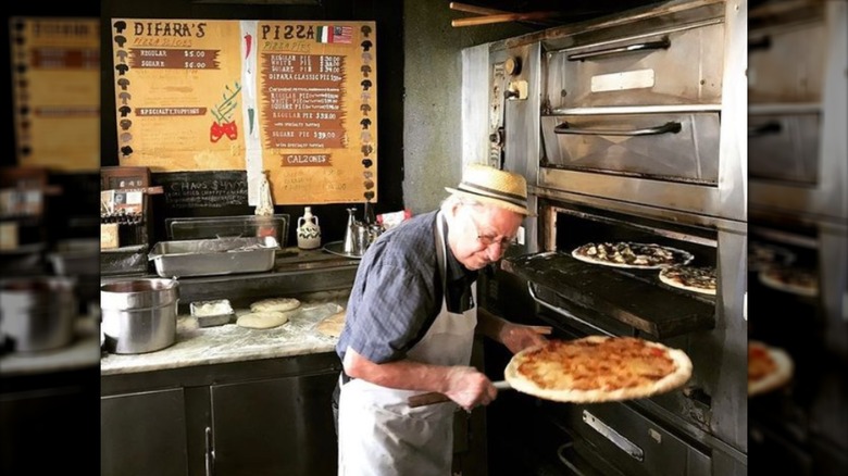 Dom De Marco pulling a pizza out of the oven