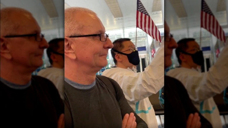 Robert Irvine smiling next to American flag 