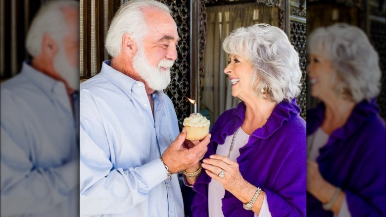 Michael Groover smiles with Paula Deen while holding cupcake