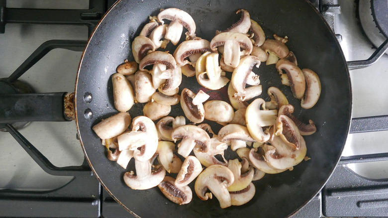 Sliced mushrooms in a frying pan.