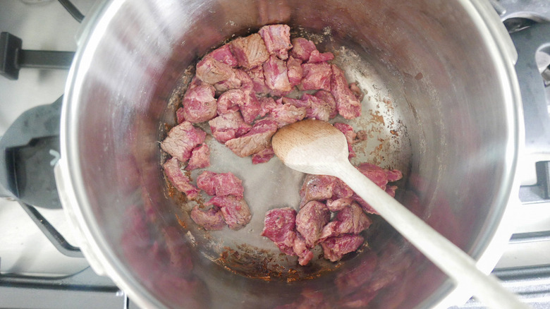 Cooking sliced beef in a pot.