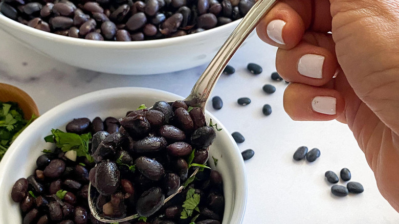 hand picking up spoonful of beans