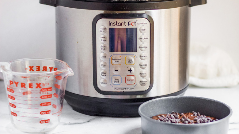 A measuring cup and brownie dish in front of an Instant pot