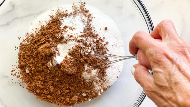 hand whisking dry cake ingredients in bowl