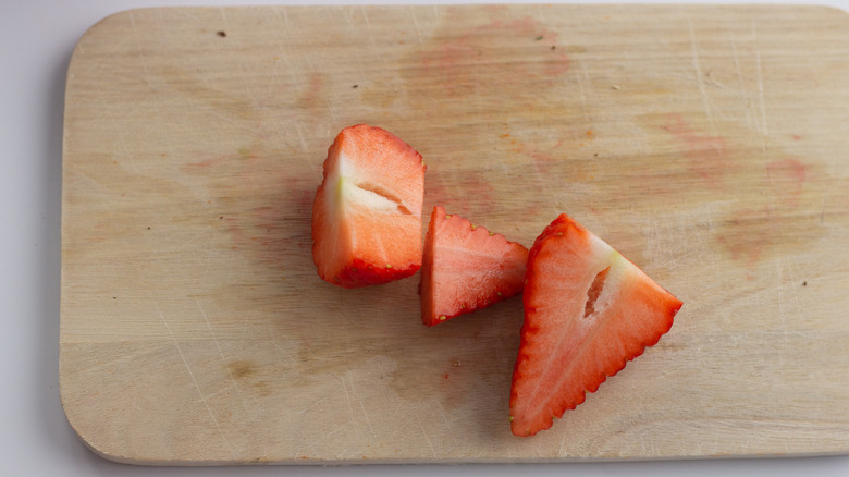 fresh red ripe strawberry quartered on a wooden cutting board