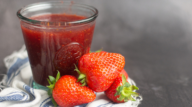 fresh red ripe strawberries on a towel next to a glass jar of instant pot homemade strawberry jam