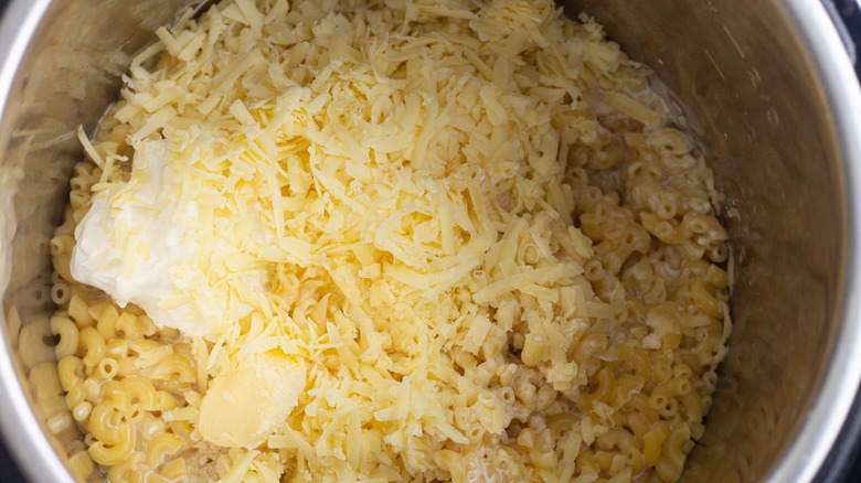 adding butter and cheese to noodles