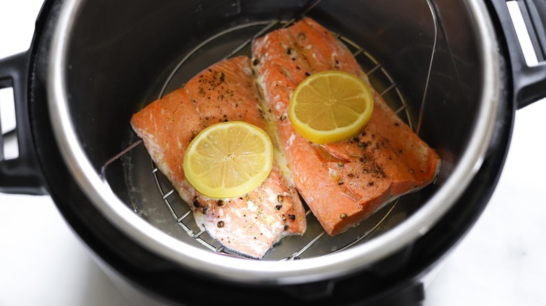 Overhead shot of two salmon fillets with lemon slices cooking in an Instant Pot