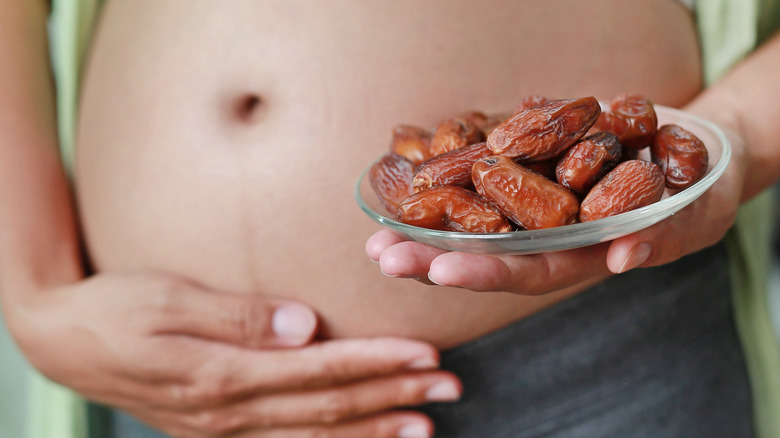 pregnant person holding bowl of dates