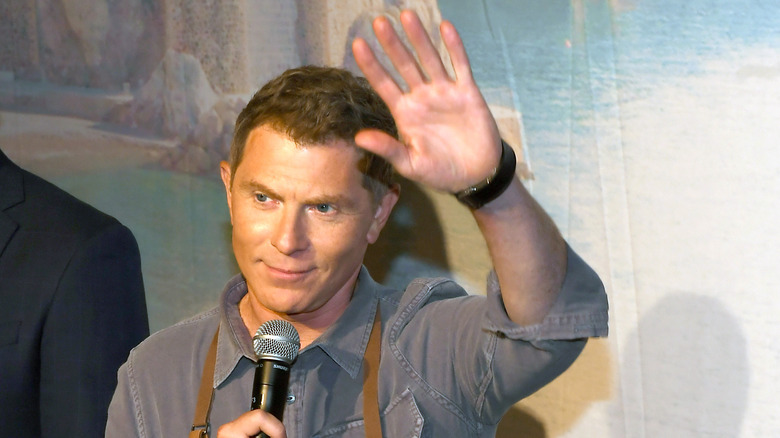 Bobby Flay waving with microphone in hand