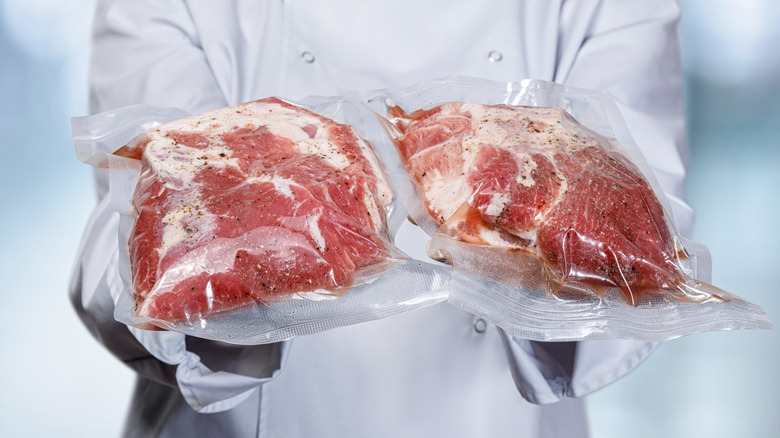 Chef holding two seasoned sous vide steaks