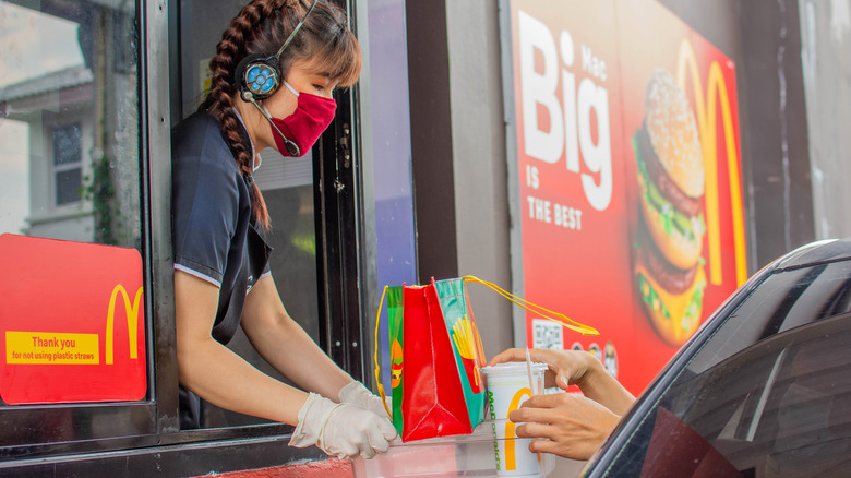 Person in red mask handing food