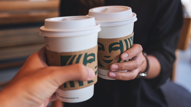 Two people toasting with Starbucks cups