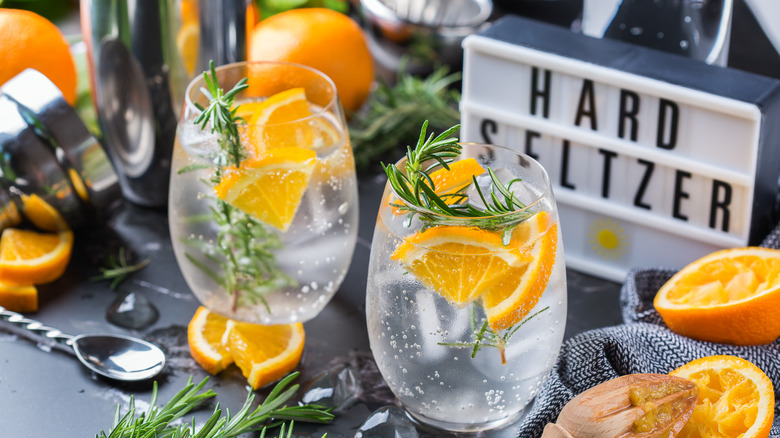 Hard seltzer in stemless mugs with orange and rosemary