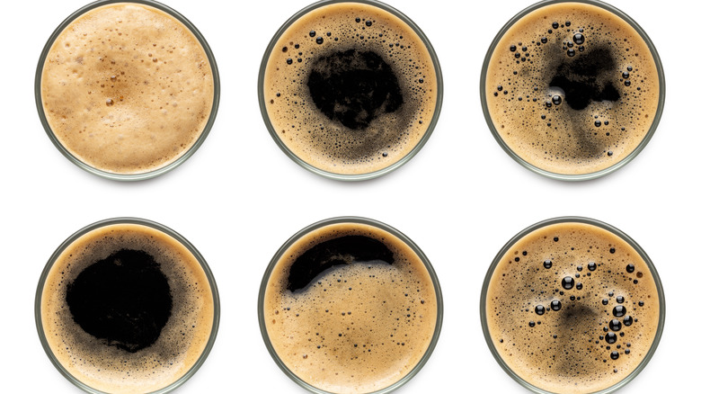 Top view of six glasses of dark beer with foam