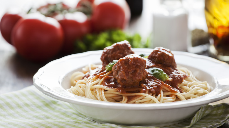 Spaghetti and meatballs near tomatoes