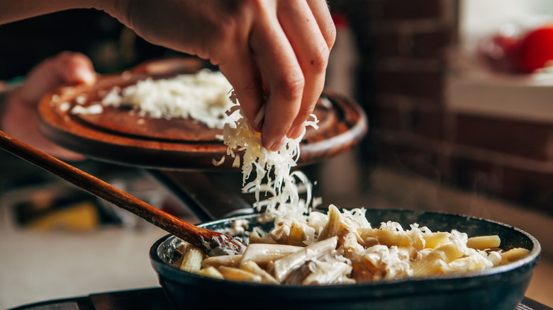 sprinkling parmesan on pasta