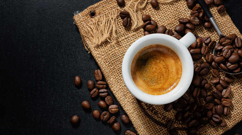 Cup of espresso with coffee beans around it