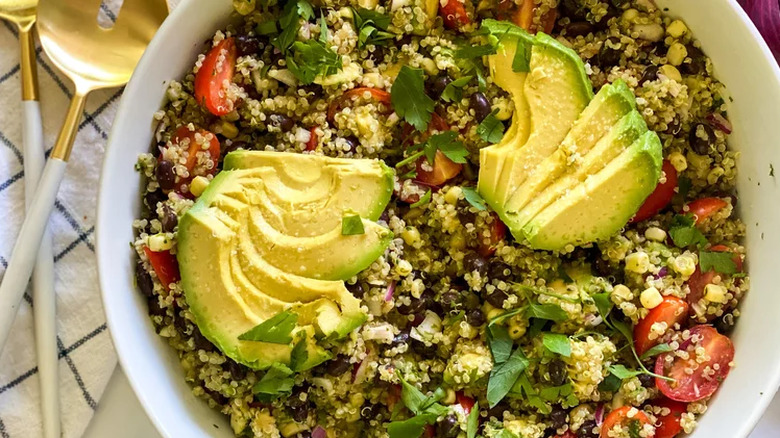 Large bowl of quinoa salad with sliced avocado. 