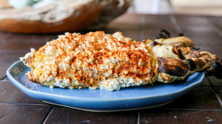 Ears of cooked corn with creamy sauce and red spices. 