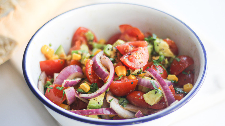 Salad with red onion, tomatoes, avocado, and corn. 