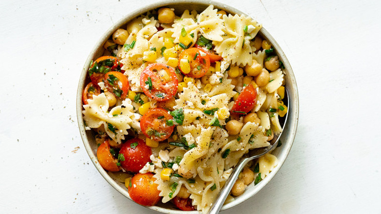 Bowl of pasta salad with tomatoes and herbs. 