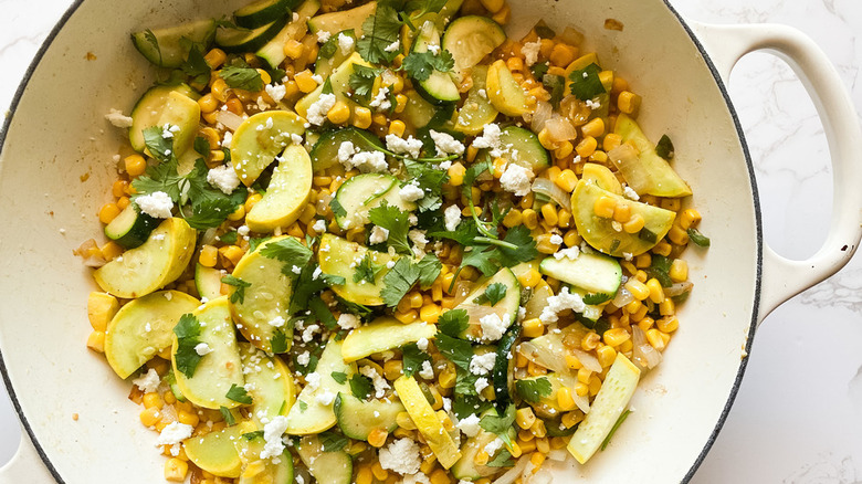 Stock pot with mix of corn, zucchini, and herbs. 