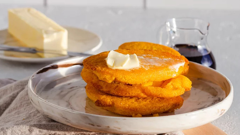 Fried corn pone cakes with butter on a plate. 