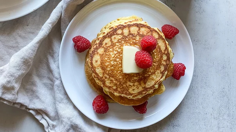 Cornmeal pancakes with butter and red raspberries.