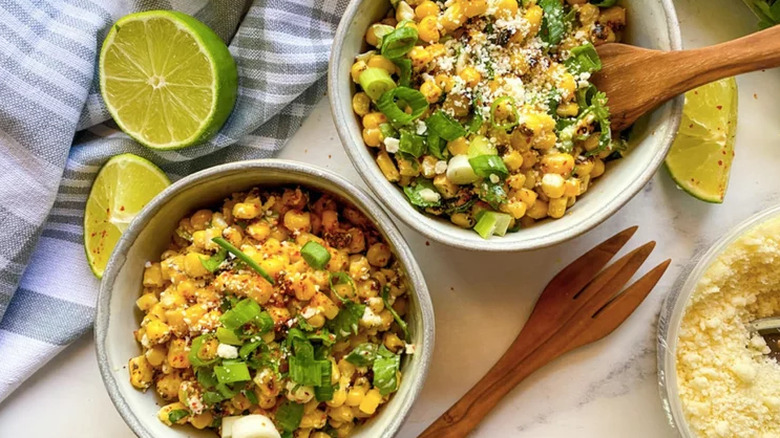 Bowls of corn salad with scallions and limes. 