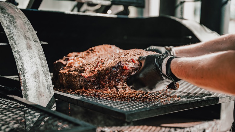 Pitmaster handling beef with black gloves