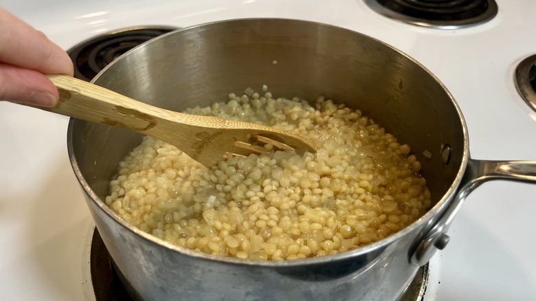 stirring cooked couscous in pot