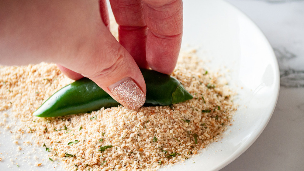 dipping jalapeño poppers in breadcrumbs