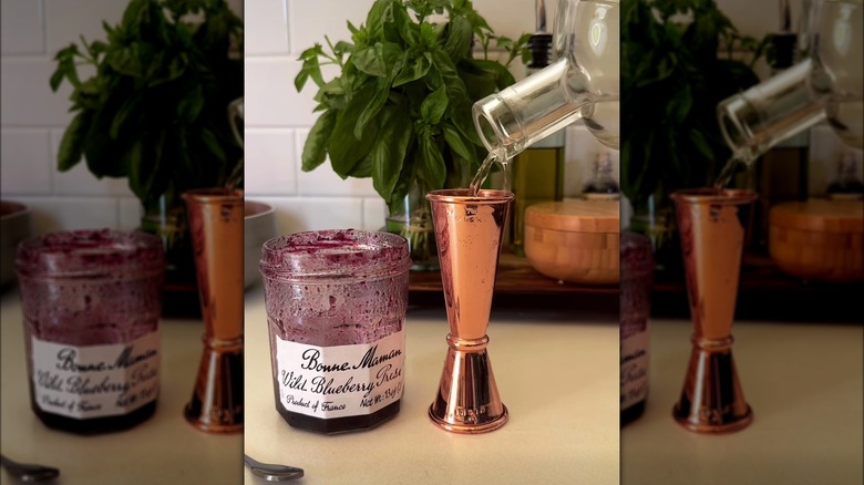 nearly empty jam jar with jigger filled with liquor