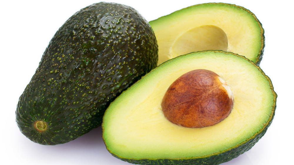 Whole and cut avocados on white background