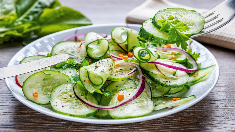 pickled cucumbers and red onion in a salad bowl with fork and knife