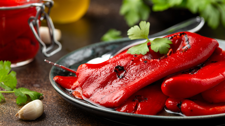 Roasted red peppers with a jar in the background