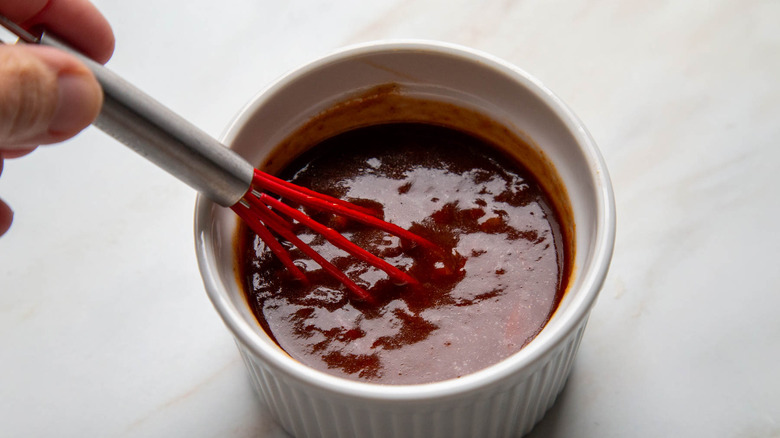 Hand whisking bbq sauce in bowl