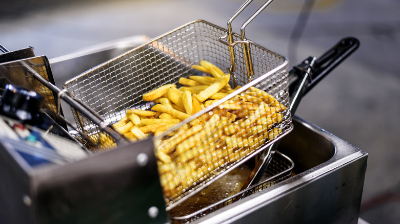 French fries in fryer basket over oil