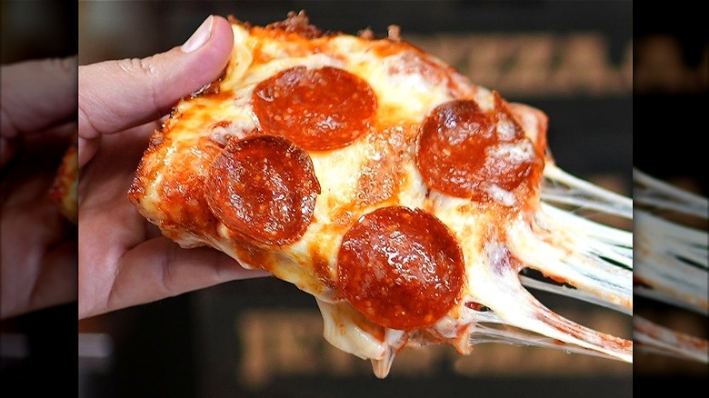 Hand holding Pepperoni Slice