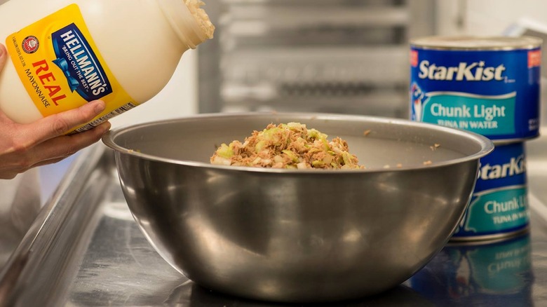 Employee adding mayo to tuna salad