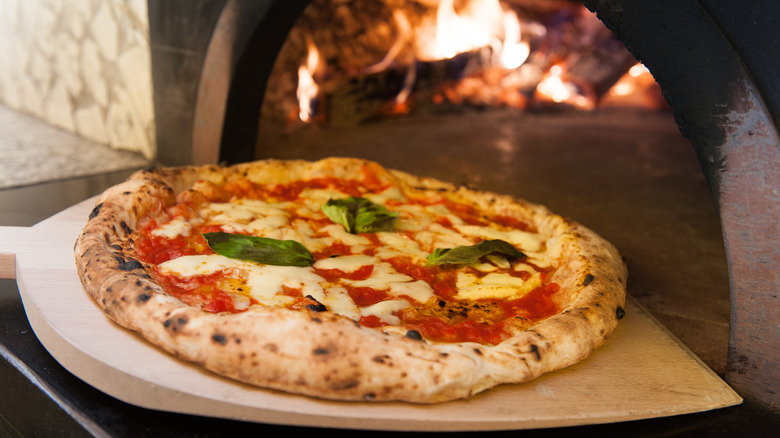 Putting a pizza into an oven on a wood spatula