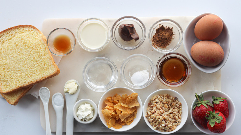 French toast ingredients including bread, eggs, Nutella, nuts, strawberries, syrup and butter