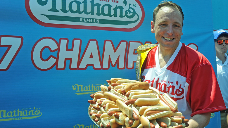 Joey Chestnut holding plate of hot dogs