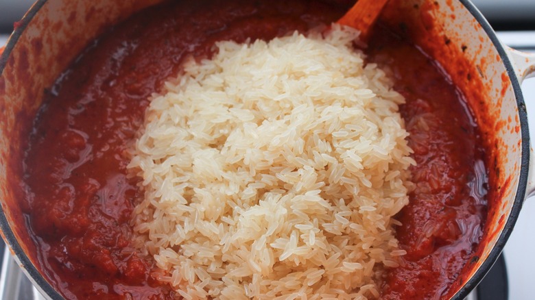 Adding rice to the simmering tomato sauce